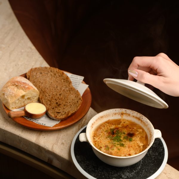 Onion gratin soup at The Royal Saigon, served with toasted bread and melted cheese in a warm dining setting.