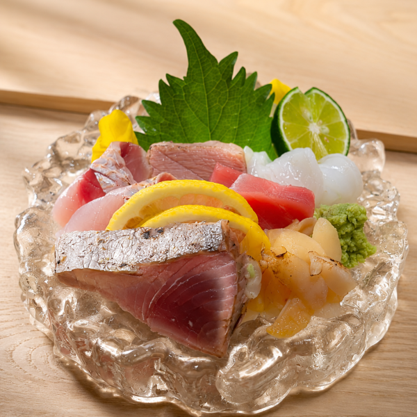 Seasonal sashimi platter at Roll Ineya Saigon, featuring fresh Japanese seafood, shiso, wasabi and citrus garnish.