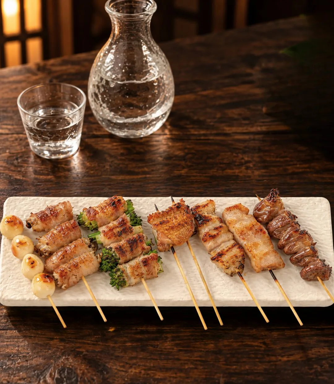 An izakaya table with grilled skewers and sake