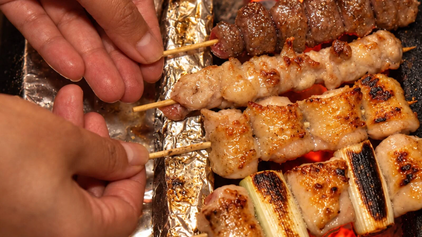 Yakitori skewers grilling over glowing binchotan charcoal