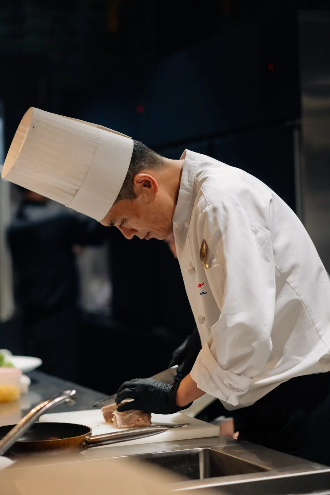 A chef preparing a dish at the open kitchen counter